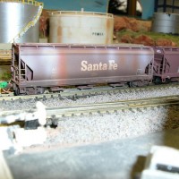 Two Santa Fe covered hoppers with elongated hatches one is weathered and other isn't