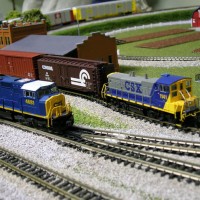 A MP15 CSX switcher waits to move some boxcars while train #4681 rolls by