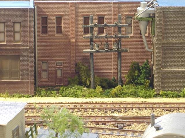 Sand Springs Railway - Power poles on window backdrop. buildings kitbashed, poles scratch built.